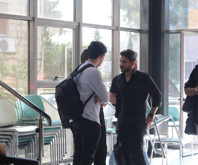 Group of people having a conversation in a brightly lit indoor space with large windows.
