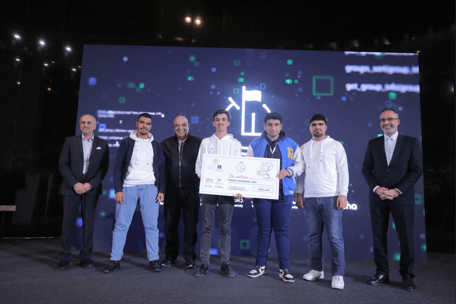 Group of people on stage holding a large ceremonial check in front of a digital backdrop.